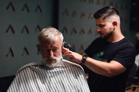 Handsome awesome barber working with electic shaver Stock Photos