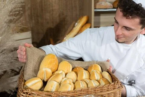 A handsome baker serves fresh bread to thirsty customers. Sale of bread in a Foto stock