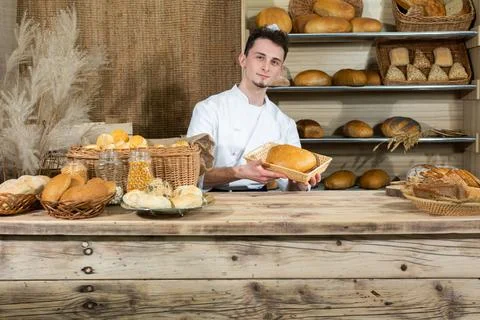 A handsome baker serves fresh bread to thirsty customers. Sale of bread in a 写真素材