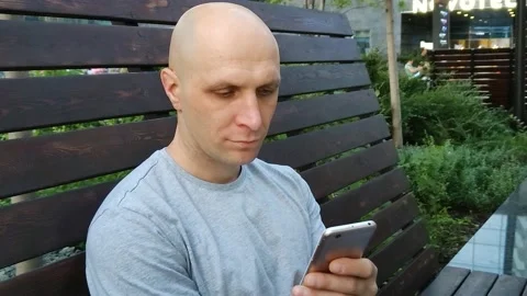 Handsome bald guy look at mobile phone screen Stockbeeldmateriaal 207009822