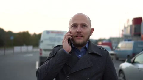 Handsome bald-headed man with beard talking on cellphone. Blury steady shot Stock Footage 97117508