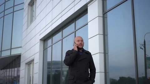 Handsome bald-headed man with beard talking on cellphone at the bussines center Stock Footage 97117950