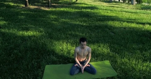 Handsome bare-chested man is meditating. Man doing yoga on exercise mat  Stock Footage 77335138
