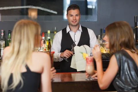 Handsome bartender working while gorgeous women talking Stock Photos