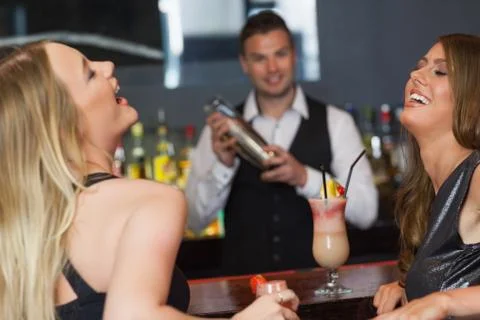 Handsome bartender working while gorgeous friends laughing Stock Photos