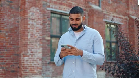 Handsome beaded man communicating with girlfriend using mobile app on cellphone Stock Footage 250387488