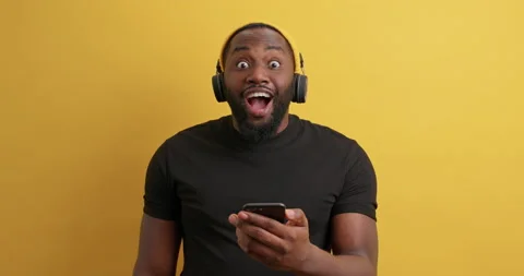 Handsome bearded black man chooses song from playlist holds modern smartphone Stock Footage 150296167