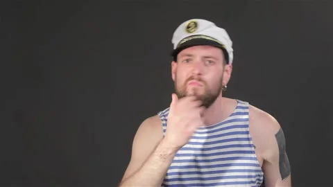 Handsome bearded captain tiding himself isolated on dark gray background Stock Footage 251464333