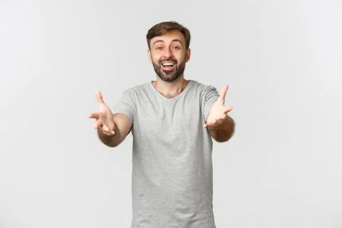 Handsome bearded caucasian man in basic grey t-shirt, stretching hands and Stock Photos