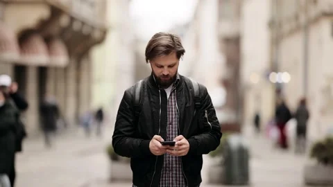 Handsome bearded Caucasian man Using a Smartphone on a Street. He Smiles and Stock Footage 152632901