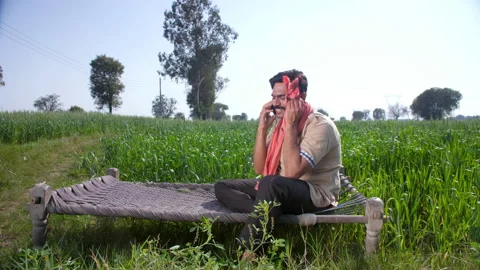 A handsome bearded farmer talking on his smartphone while relaxing on a Chaar... 스톡 동영상 193426705