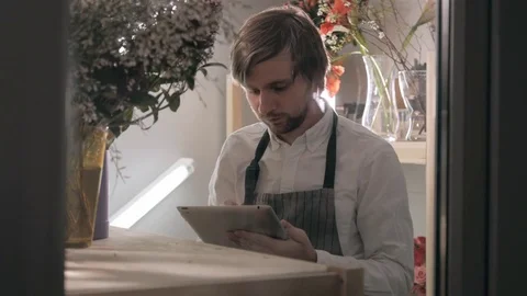 Handsome bearded florist with tablet computer at workplace in refrigerator Stock Footage 71979160