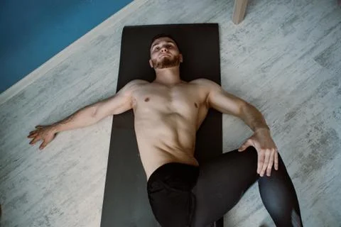 Handsome bearded guy doing stretching on a ground at home Foto stock