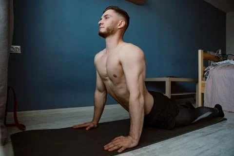 Handsome bearded guy doing stretching on a ground at home Stock Photos