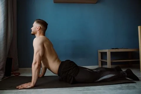 Handsome bearded guy doing stretching on a ground at home Stock Photos