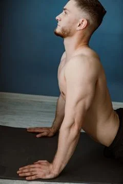 Handsome bearded guy doing stretching on a ground at home Stock Photos