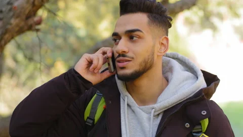 Handsome bearded hispanic man talking on mobile phone at forest trees background Stock Footage 165846669