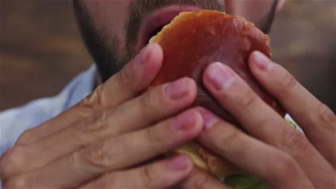 Handsome bearded man bite and eat healthy  burger with  vegetables close up Stock Footage 132331422