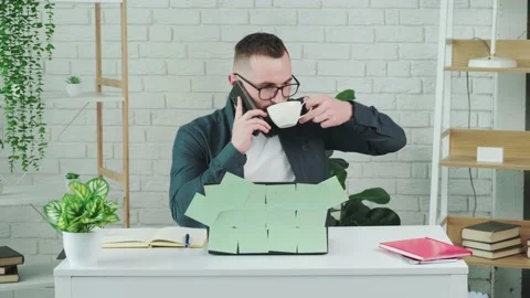Handsome bearded man drinking coffee while talking on a smart phone. Stock Footage 155404067