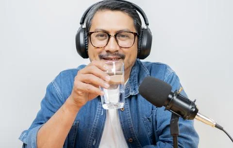 Handsome bearded man drinking a cup of water while recording podcast with p.. Stock Photos