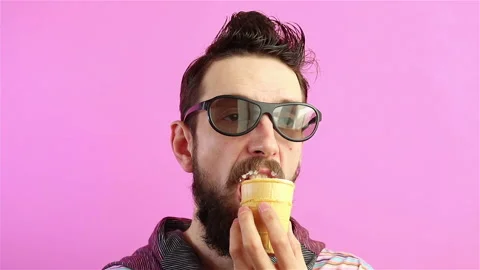 Handsome bearded man eats ice cream on pink background Stock Footage 129502910