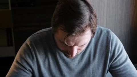 Handsome bearded man has lunch sitting at the kitchen table at home. Male eating Stock Footage 333118961