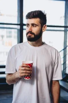 Handsome bearded man with long beard has stylish hair on serious face holding Stock Photos