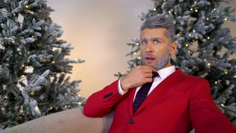 Handsome bearded man in a red suit on armchair looks to the side in copy space Video stock 167650733
