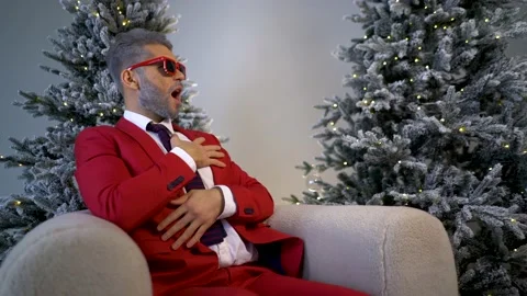 Handsome bearded man in red suit on an armchair looks to the side in copy space Video stock 167650840