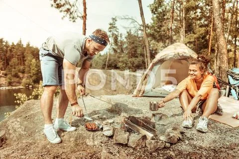 Handsome bearded man serving delicious grilled sausages Stock Photos