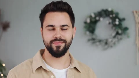 Handsome bearded man smiles at camera, feeling festive on Christmas backdrop. Video stock 253183620