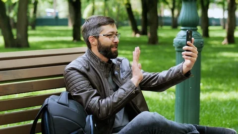 Handsome bearded man smiling, video call on the phone, at the park. Stock Footage 107986938