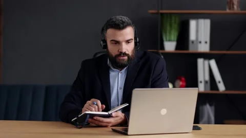 Handsome bearded man studying online using laptop web camera, writing lecture in 스톡 동영상 158236805