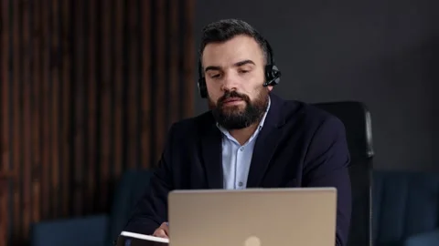 Handsome bearded man studying online using laptop web camera, writing lecture in Stock Footage 162467884