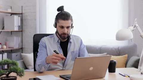 Handsome bearded man studying online using laptop web camera, writing lecture in Stock Footage 181503148