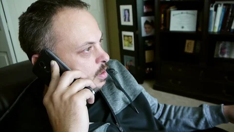 Handsome bearded man is talking over the smart phone with friend Stock Footage 77632538