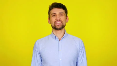 Handsome bearded man turns to the camera and smiles on a yellow background Stock Footage 130776841