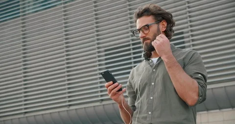 Handsome Bearded Man using Headphones and Listening to Music. Holding Smartphone Stock Footage 125147769