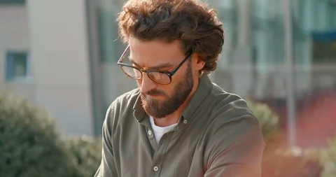 Handsome Bearded man using Smartphone and typing on sunny autumn day. Sun rays Stock Footage 125148668