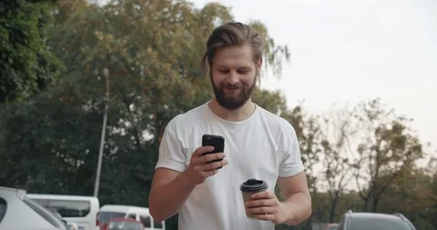 Handsome Bearded Man Walking in the While Street at Sunset. Drinking Coffee to Video stock 127126320