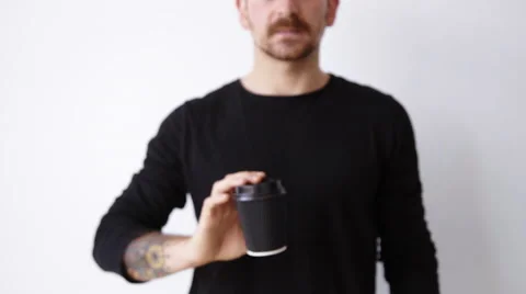 Handsome bearded unfocused guy shows paper cup on camera Stock Footage 64484807