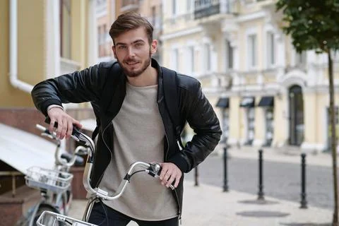 Handsome bike messenger with backpack stands near bicycle and look at camera Foto stock