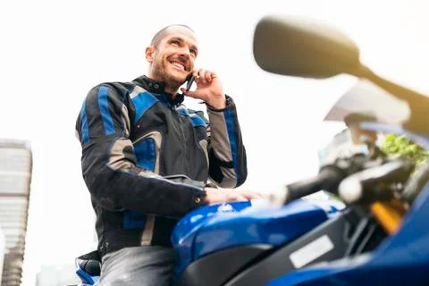 Handsome biker using mobile phone. Stock Photos