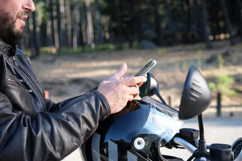 A handsome biker using mobile phone on a rural road. Foto stock