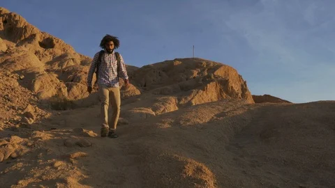 Handsome black male with dreadlocks going down on a cliff at sunrise Stock Footage 101368717