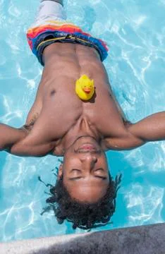Handsome black man floats at the pool Stock Photos