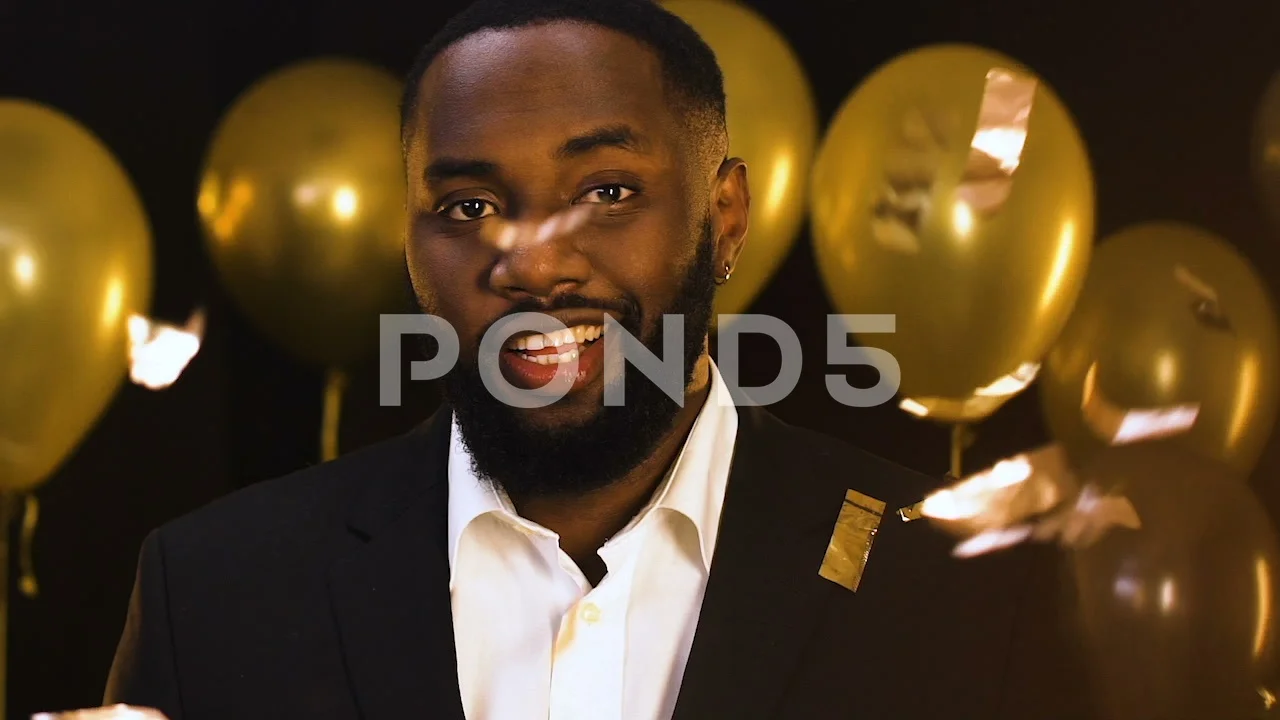 Handsome black man winking to camera at party under falling confetti,  flirting