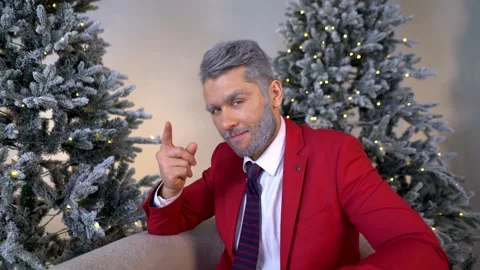 Handsome blond bearded man in a red suit on an armchair looks towards the screen Stock Footage 167648596