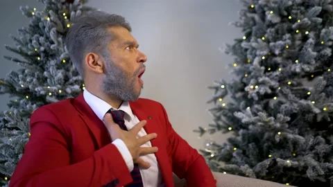 Handsome blond bearded man in a red suit on an armchair looks to the side Stock Footage 167649475