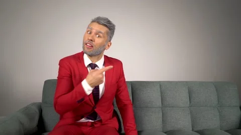 Handsome blond bearded man in red suit on sofa looking to the side in copy space Stock Footage 167650889